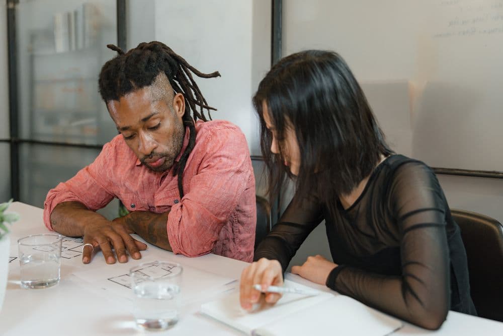 Two colleagues planning a project across a shared desk